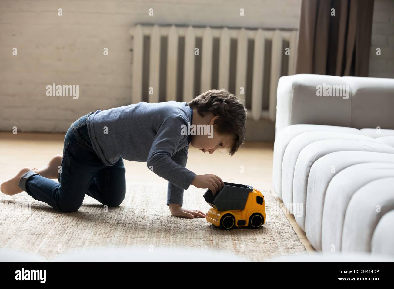 Bambino piccolo e carino felice che gioca a casa una macchina giocattolo. Foto Stock