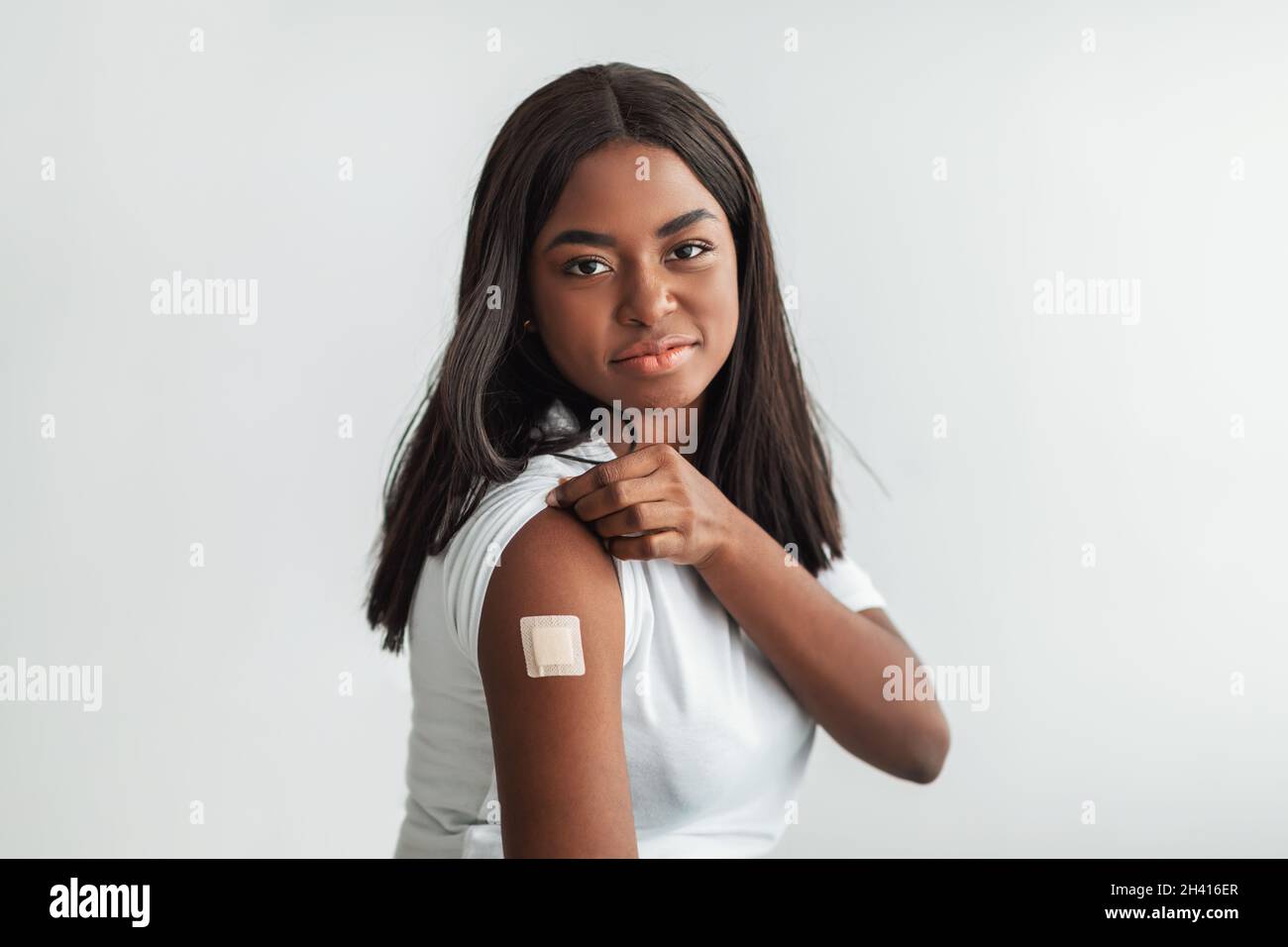 Donna vaccinata felice con bendaggio adesivo sulla spalla Foto Stock