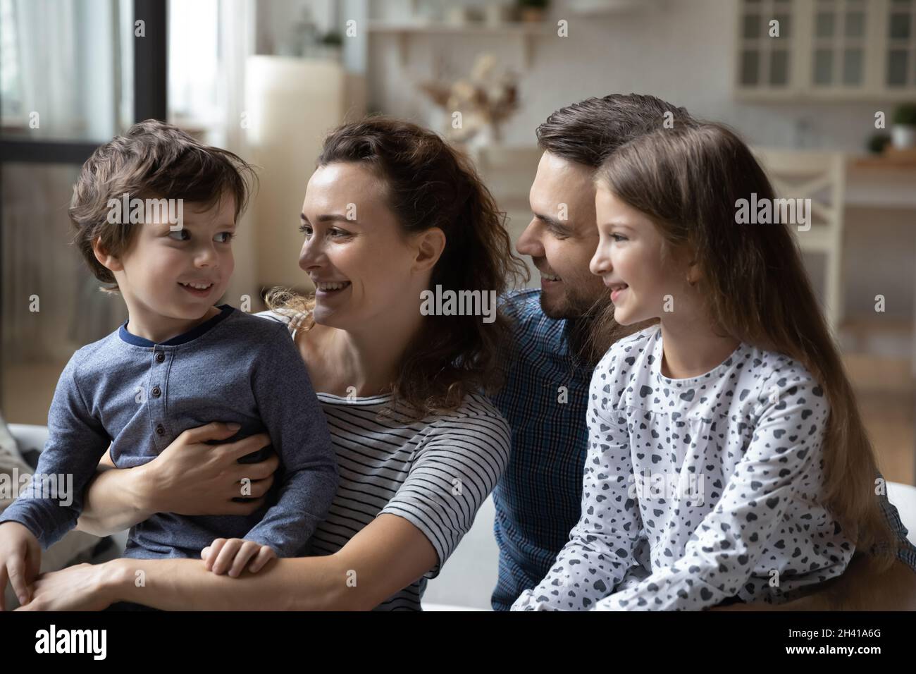 Allegro legame famiglia di quattro comunicanti, seduta sul divano. Foto Stock
