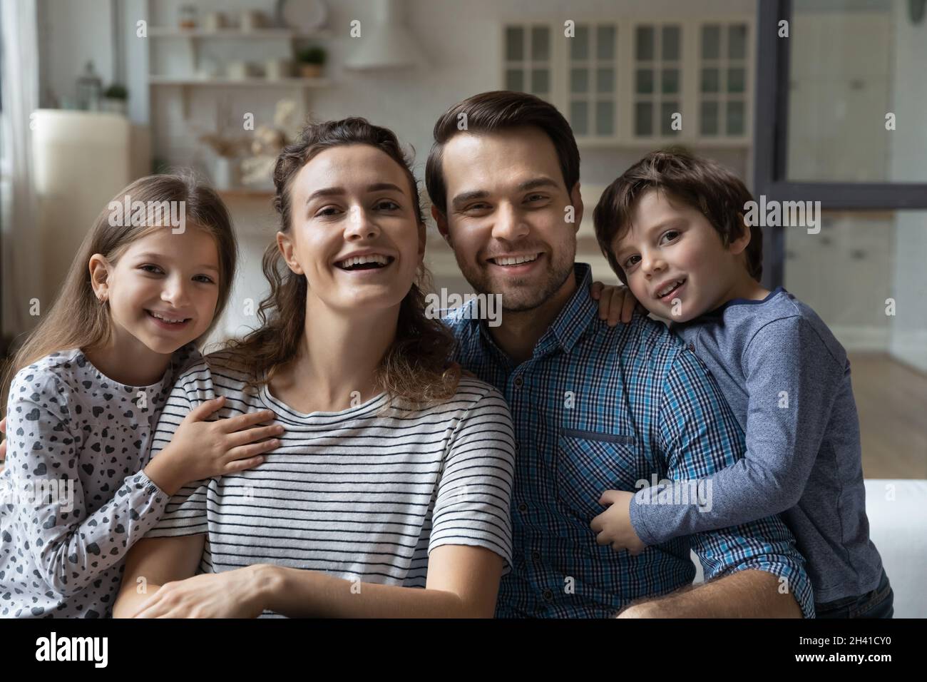Ritratto di sorridente legame genitori e bambini piccoli in posa a casa. Foto Stock
