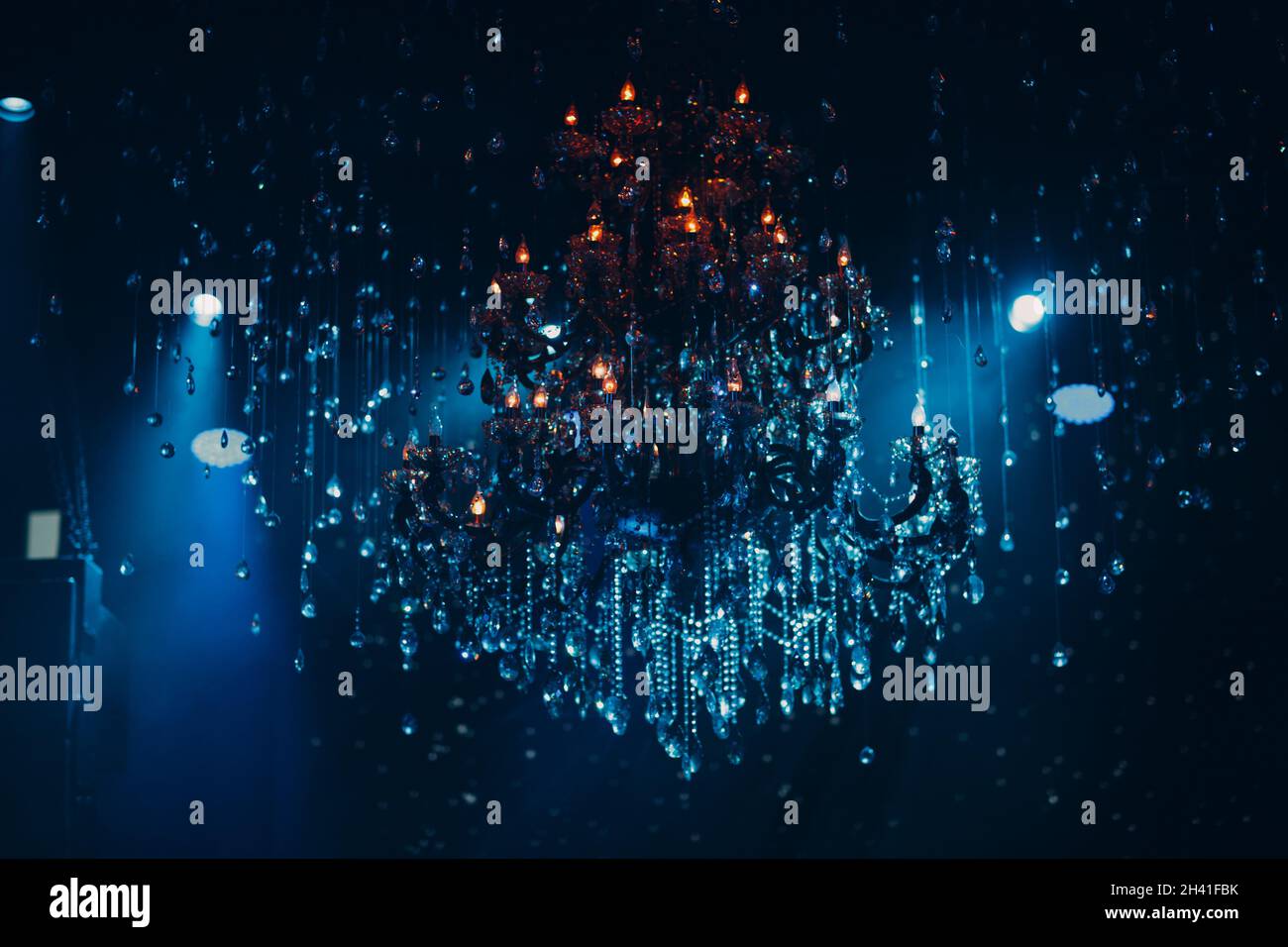Grande lampadario di cristallo illuminato con luce multicolore nel ristorante Foto Stock