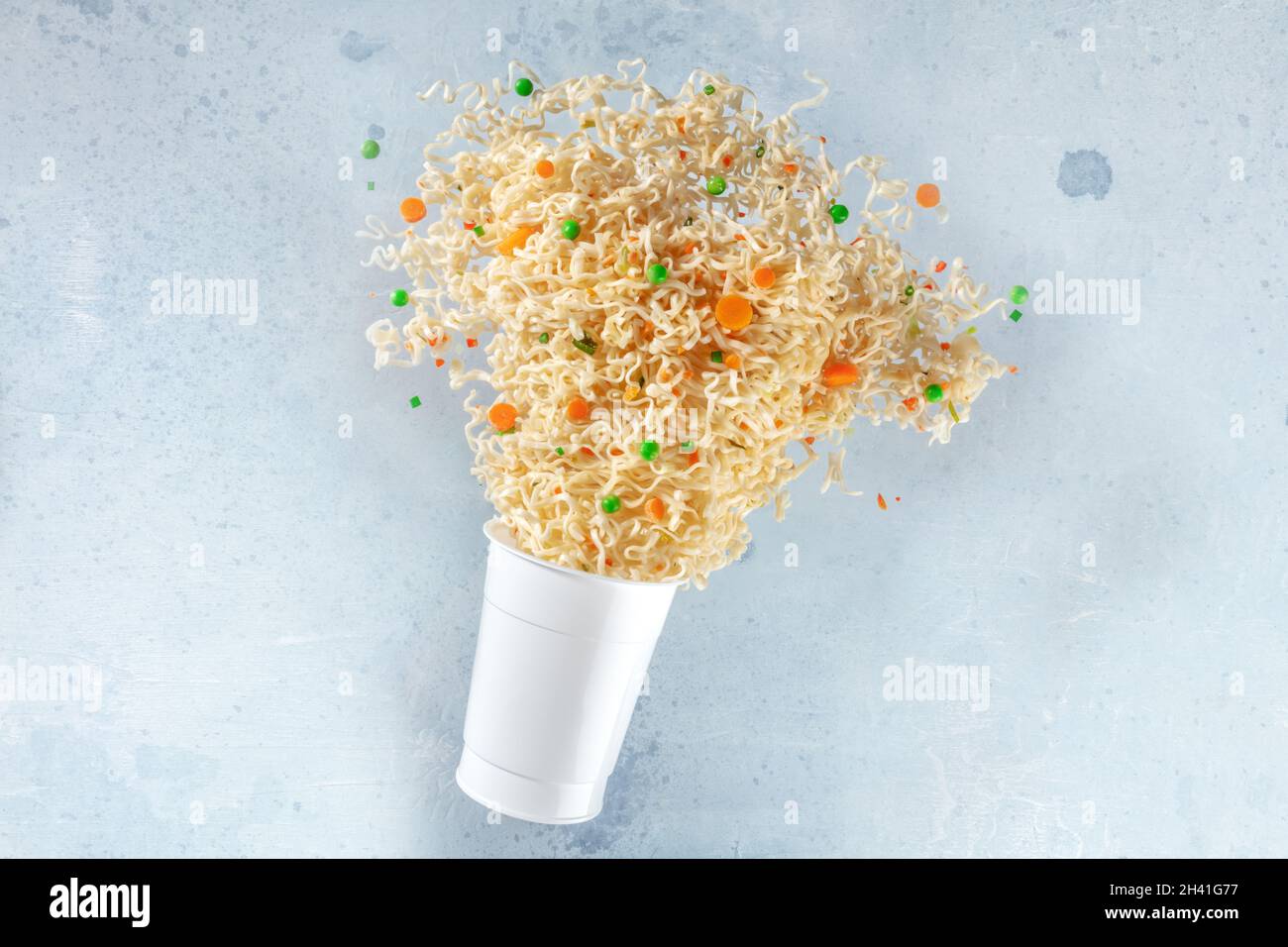 Tazza ramen con spaghetti istantanei che volano fuori di esso, levitazione veloce del cibo Foto Stock