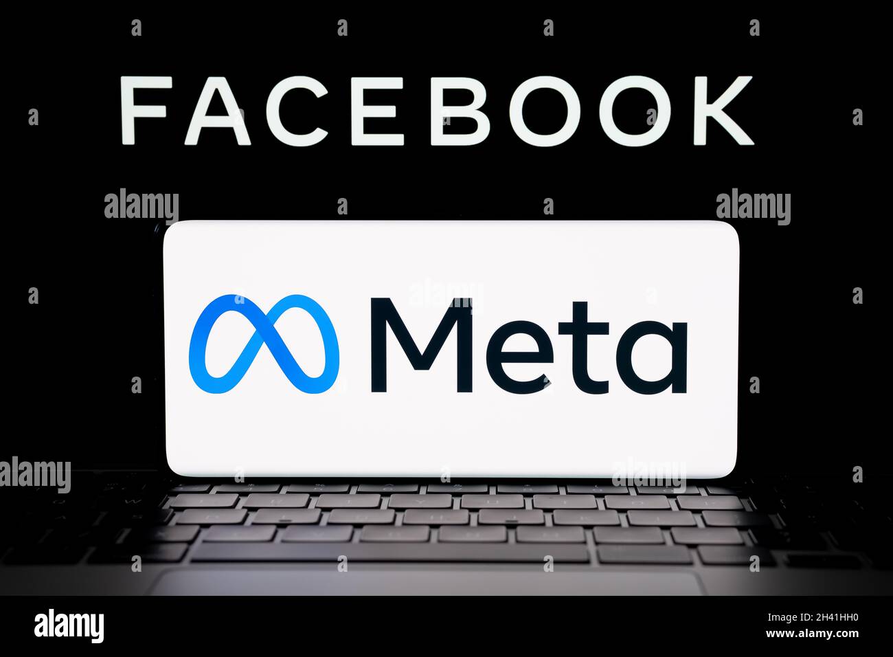 META Company logo visto smartphone che è posto sul portatile con sfocato Facebook inc logo sullo schermo. Nuovo logo Facebook. Stafford, Regno Unito, Foto Stock