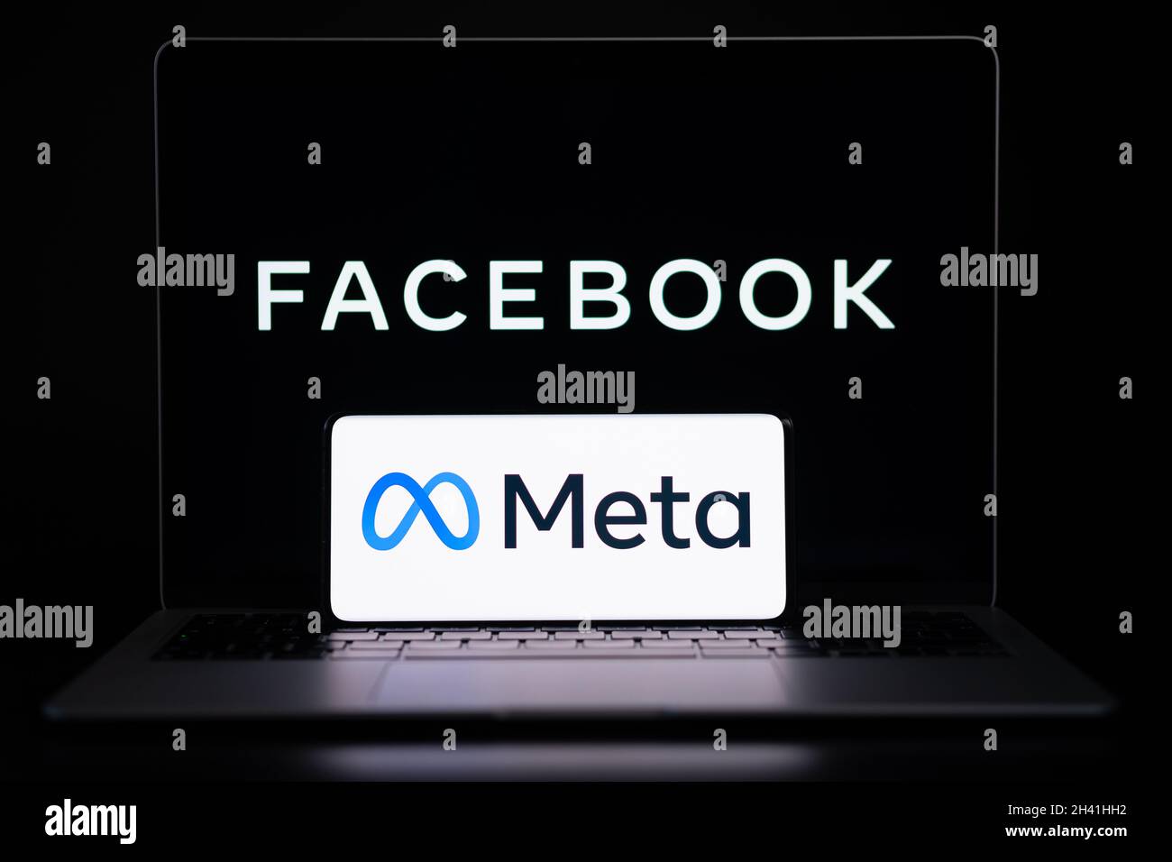 META Company logo visto smartphone che è posto sul portatile con sfocato Facebook inc logo sullo schermo. Nuovo logo Facebook. Stafford, Regno Unito, Foto Stock