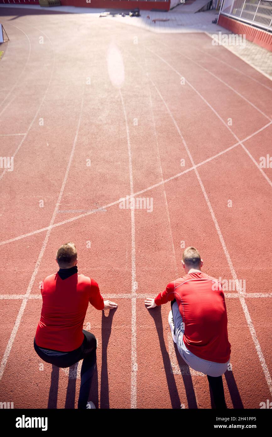 due uomini alla linea di partenza della pista atletica pronti per iniziare la gara. Immagine concettuale della concorrenza. Foto Stock
