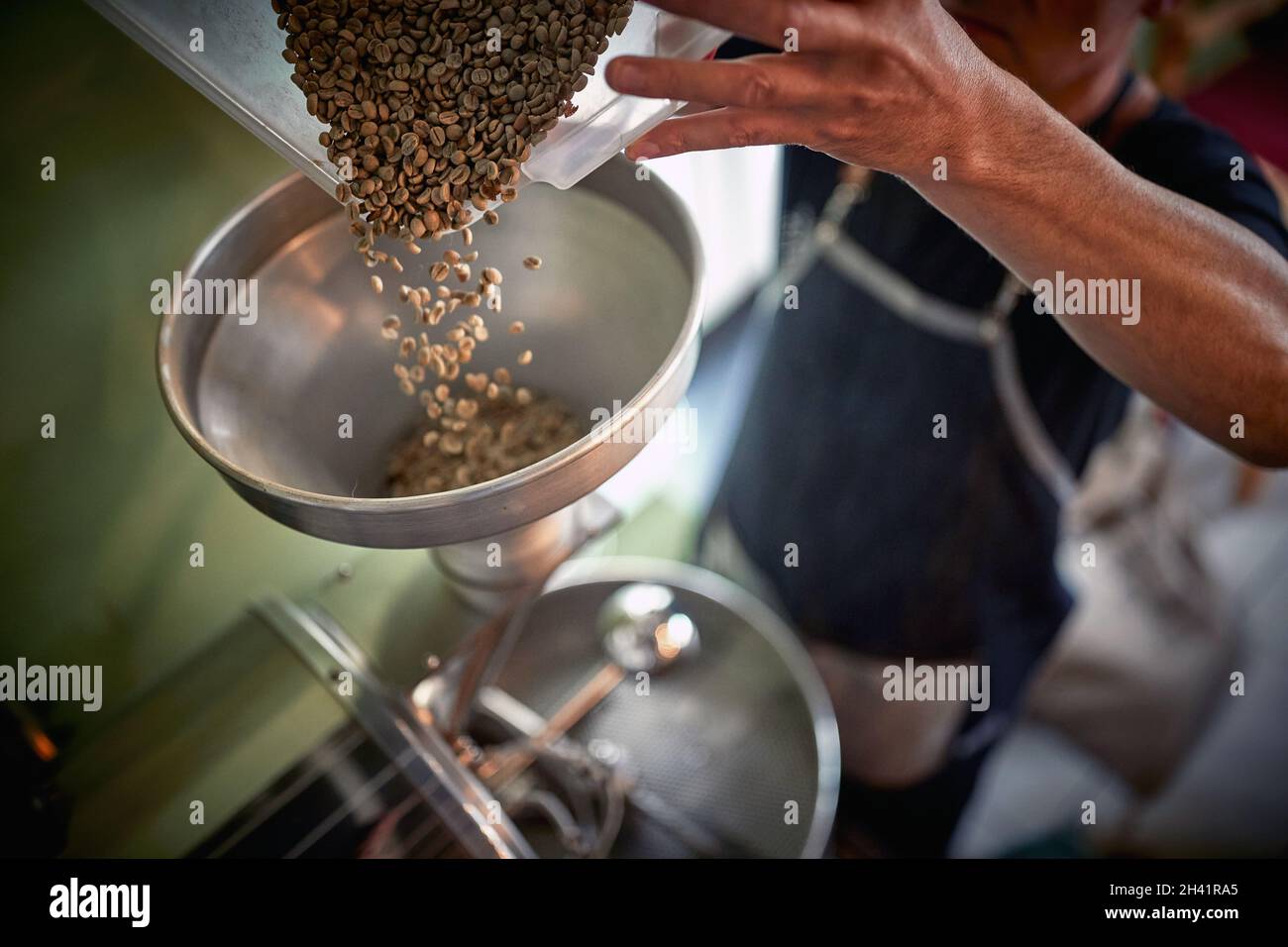 Un uomo sta facendo il caffè macinato fragrante e aromatico versando i fagioli nel macinacaffè. Caffè, bevande, produzione Foto Stock
