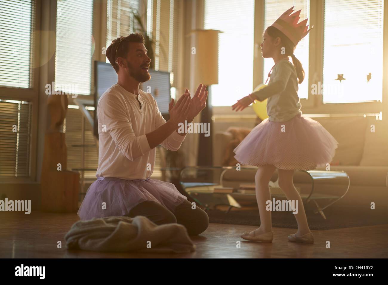 Un giovane padre che si diverse ad allenarsi in balletto in un'atmosfera rilassata a casa con la sua piccola ballerina. Famiglia, balletto, formazione Foto Stock