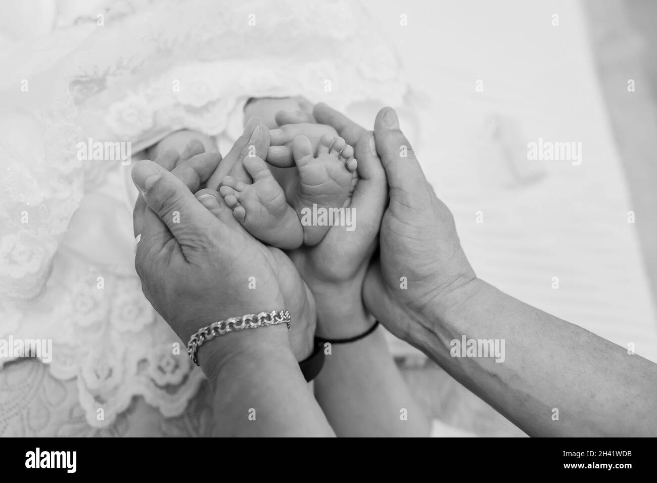 le mani che formano una cornice di cuore per i piedi piccoli del suo bambino neonato Foto Stock