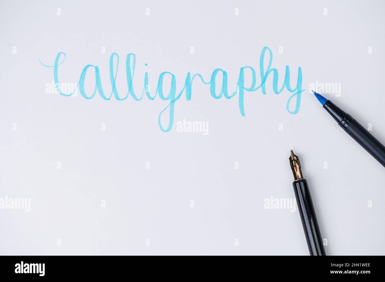 pennello penna che giace su una carta bianca, dove è scritto la parola calligrafia Foto Stock