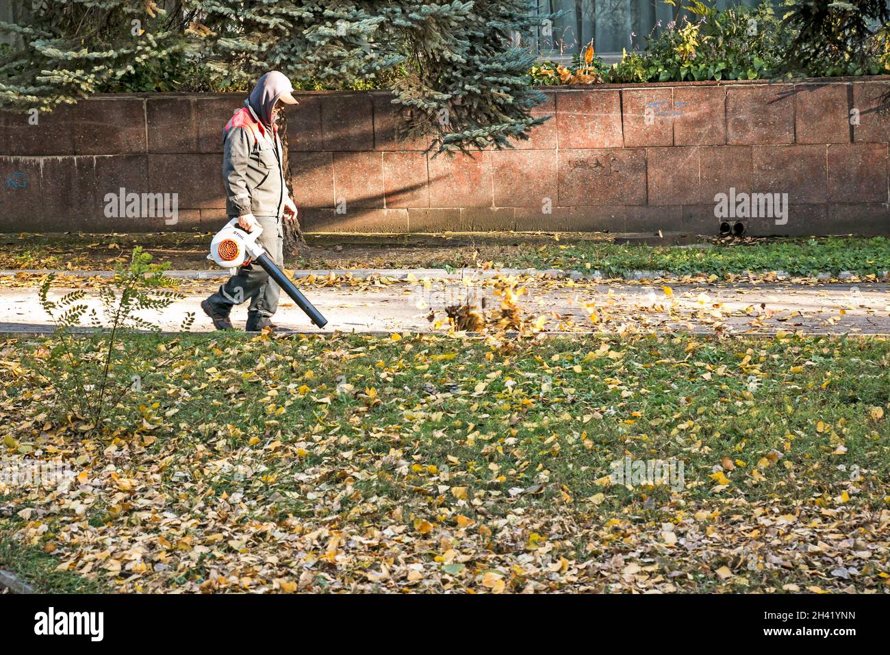 Dnepropetrovsk, Ucraina - 10.19.2021: Pulizia di foglie secche con un mulino a vento. Un lavoratore municipale pulisce il parco cittadino. Preparazione dei parchi cittadini per l'inverno Foto Stock