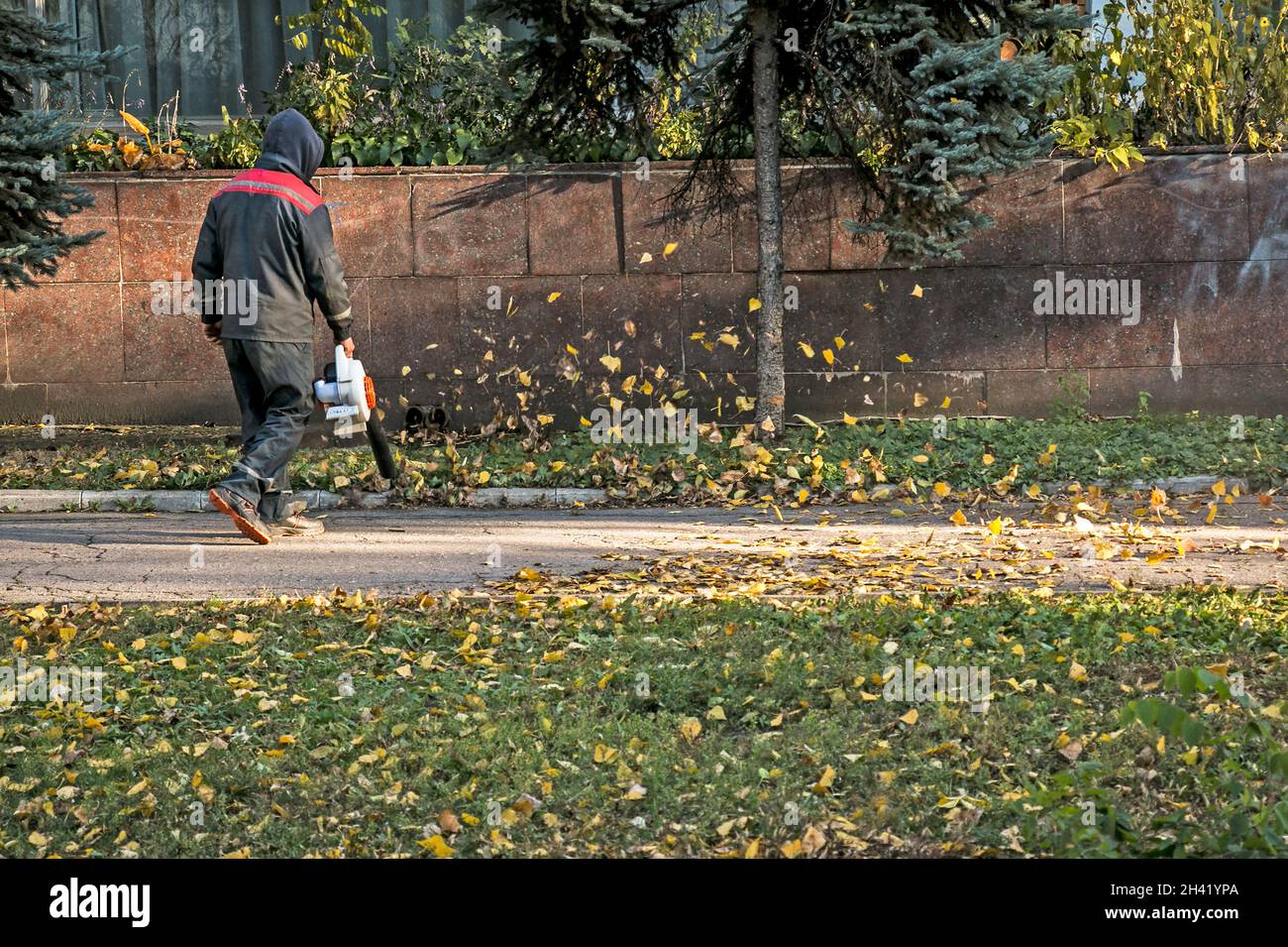 Pulizia foglie secche con un mulino a vento. Un lavoratore municipale pulisce il parco cittadino. Preparazione dei parchi cittadini per l'inverno. Foto Stock