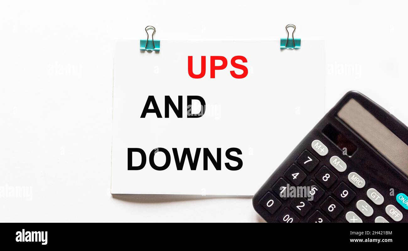 UPS e downs, il testo è scritto su uno sfondo bianco, una calcolatrice si trova nelle vicinanze. Concetto aziendale Foto Stock