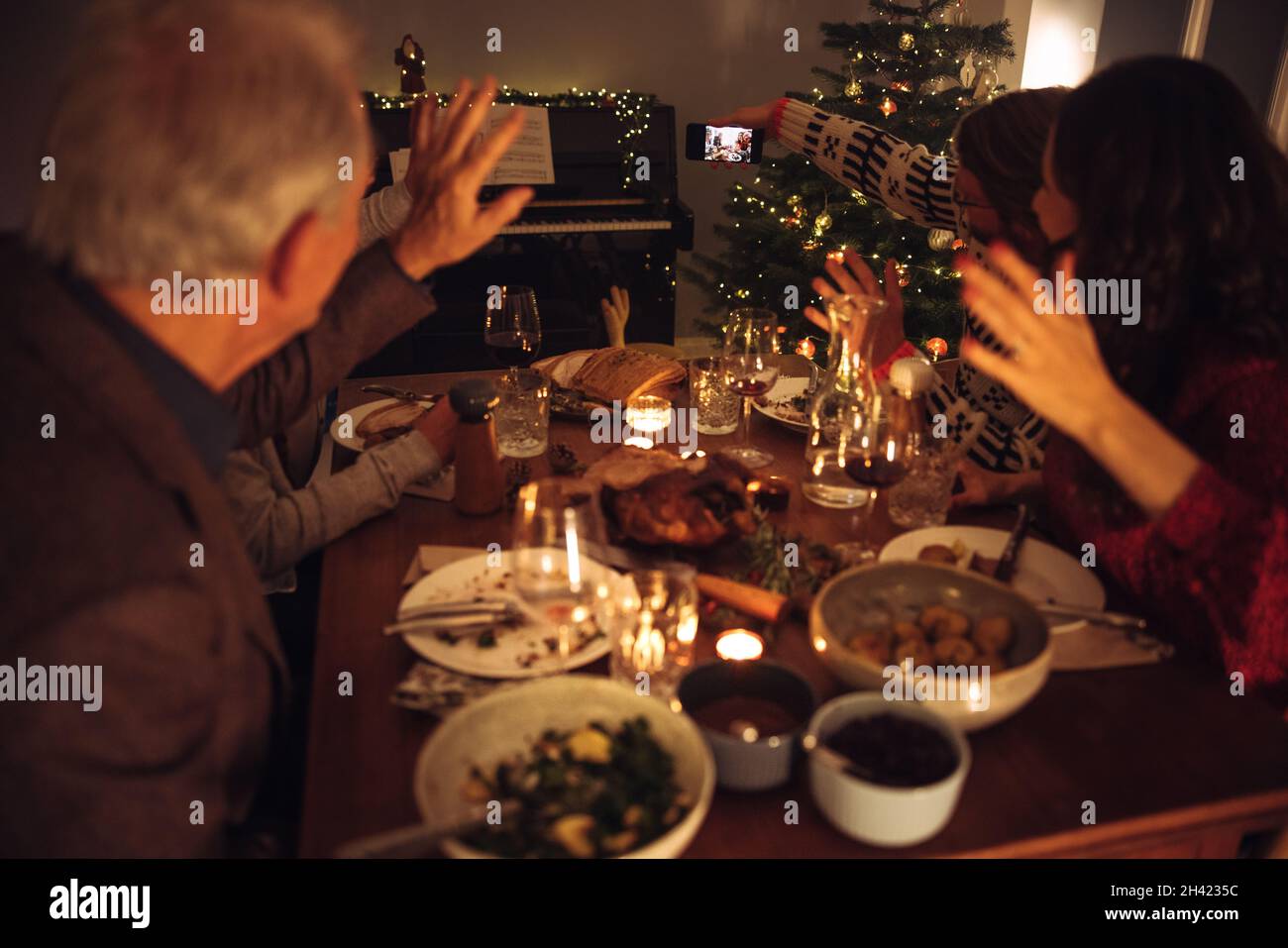 Uomo che prende selfie con la famiglia in cena della vigilia di natale. Famiglia che prende selfie durante la cena di Natale. Foto Stock