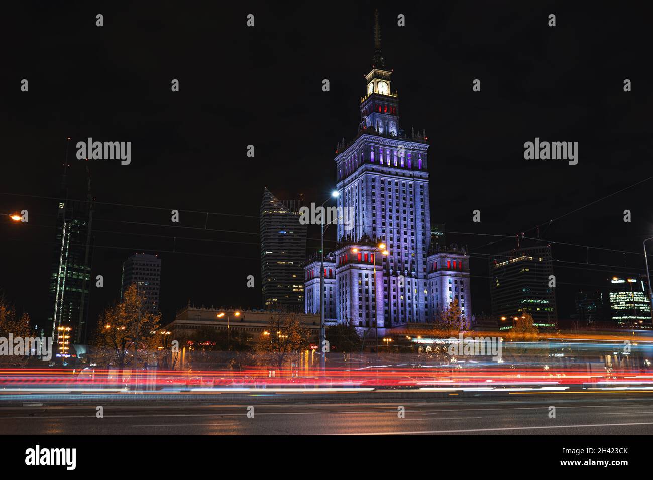 Palazzo della Cultura e della Scienza illuminato di notte nel centro di Varsavia. Semaforo e auto in movimento a lunga esposizione. Varsavia, Polonia - 23 ottobre 2021 Foto Stock