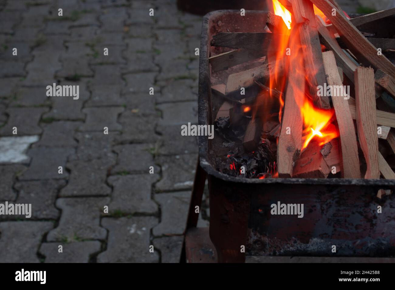 Impilato pezzi di legno in una griglia che brucia nel fuoco arancione. Preparazione per il grill di notte. Ora di cena. Foto Stock