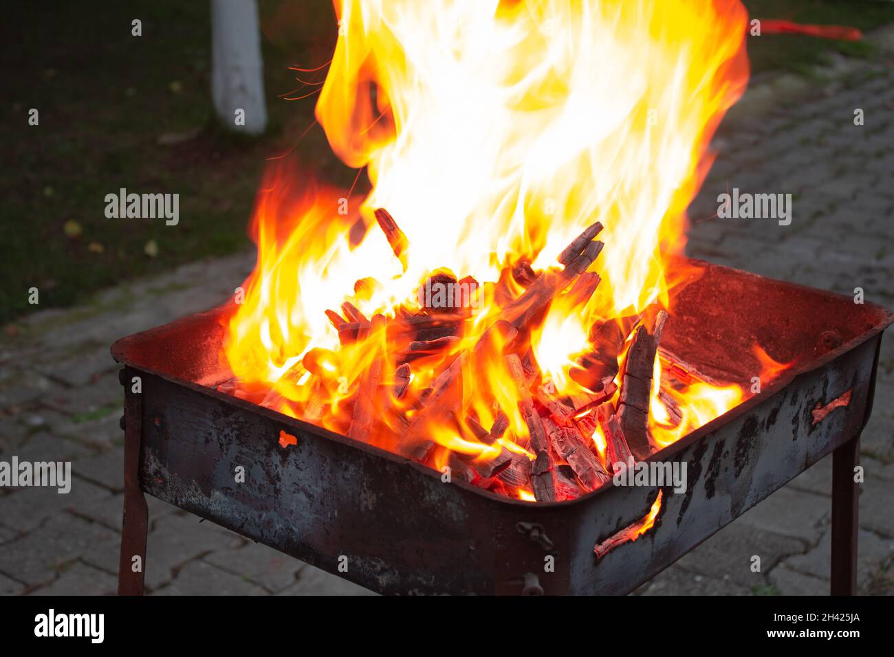 Impilato pezzi di legno in una griglia che brucia nel fuoco arancione. Preparazione per il grill di notte. Ora di cena. Foto Stock