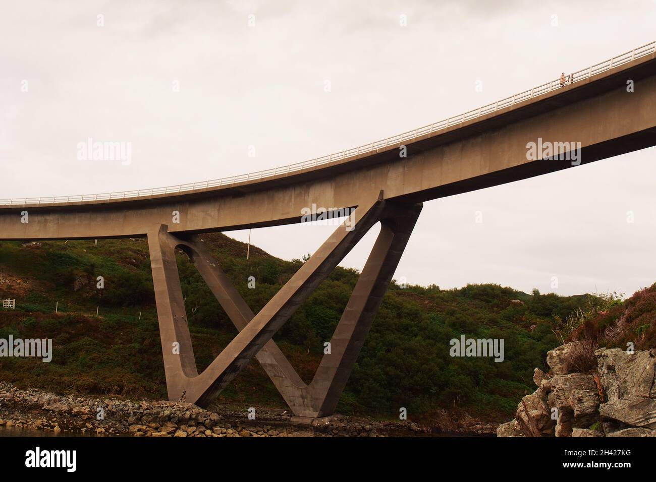 Una giovane coppia che cammina sul ponte Kylesku, Sutherland, Scozia, mostrando la lunga curva del ponte Foto Stock