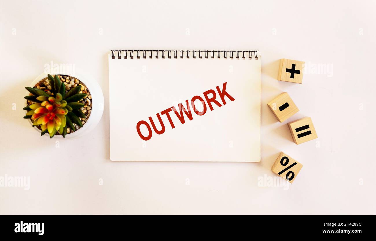 OUTWORK , il testo è scritto su un notebook e su uno sfondo bianco. Sul tavolo ci sono cubetti di legno con segni e un fiore di cactus Foto Stock