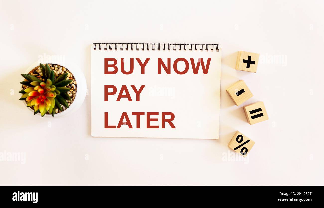 Testo Acquista ora pagare più tardi su blocco note e sfondo bianco. Cubetti con zakami più, meno, uguale e percentuale Foto Stock