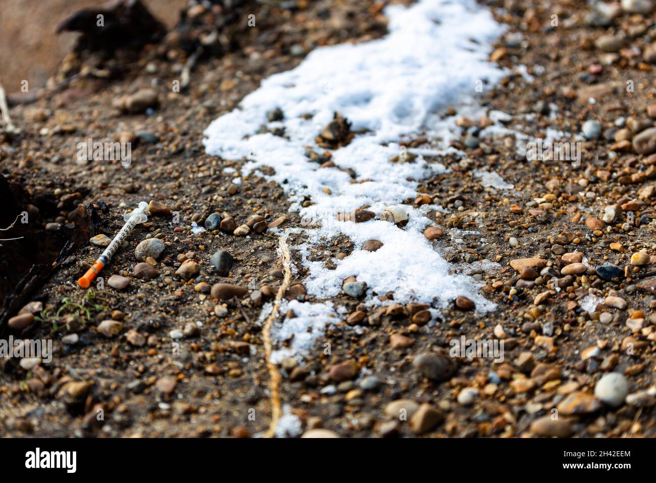 Una siringa usata che è stata scartata sul pavimento in una popolare spiaggia di Suffolk. Sembra che sia stato usato e lasciato lì da un utilizzatore di droga Foto Stock