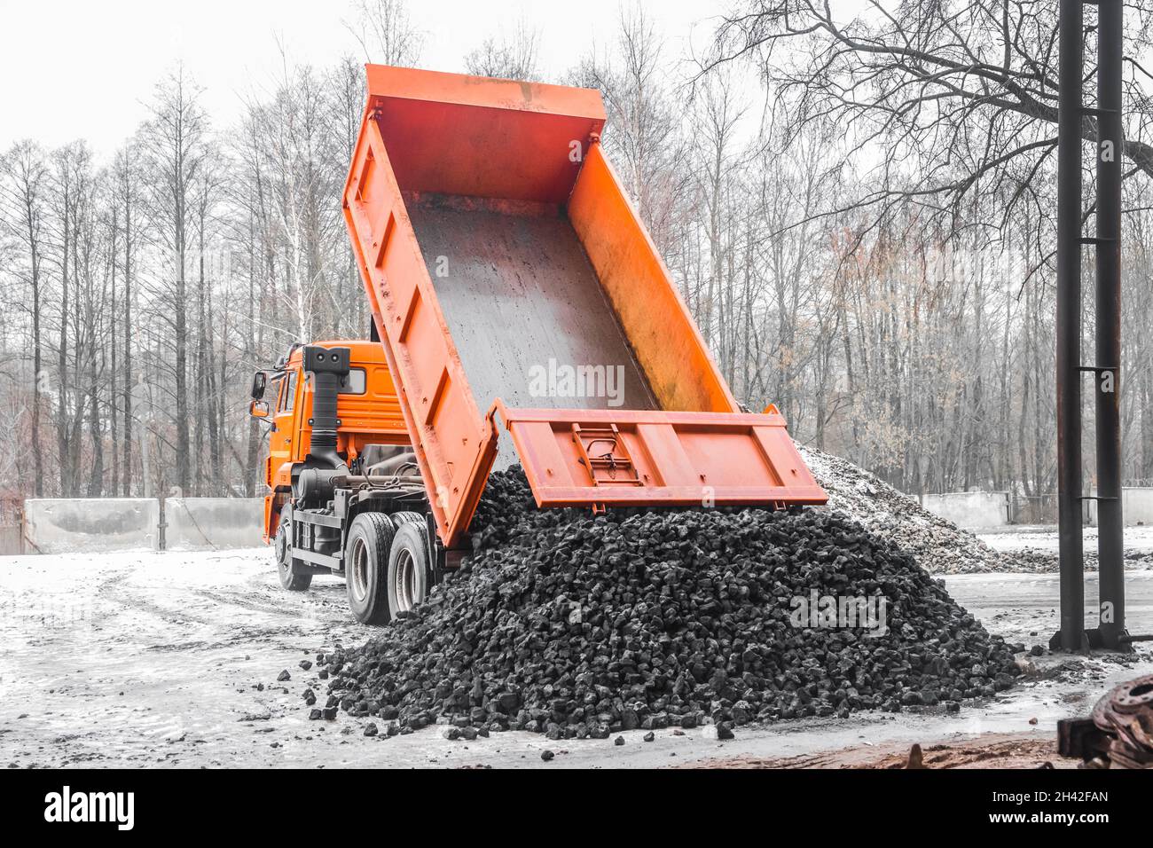 Il dumper di scarico nella zona industriale scarica il carbone da coke dalla carrozzeria. Foto Stock