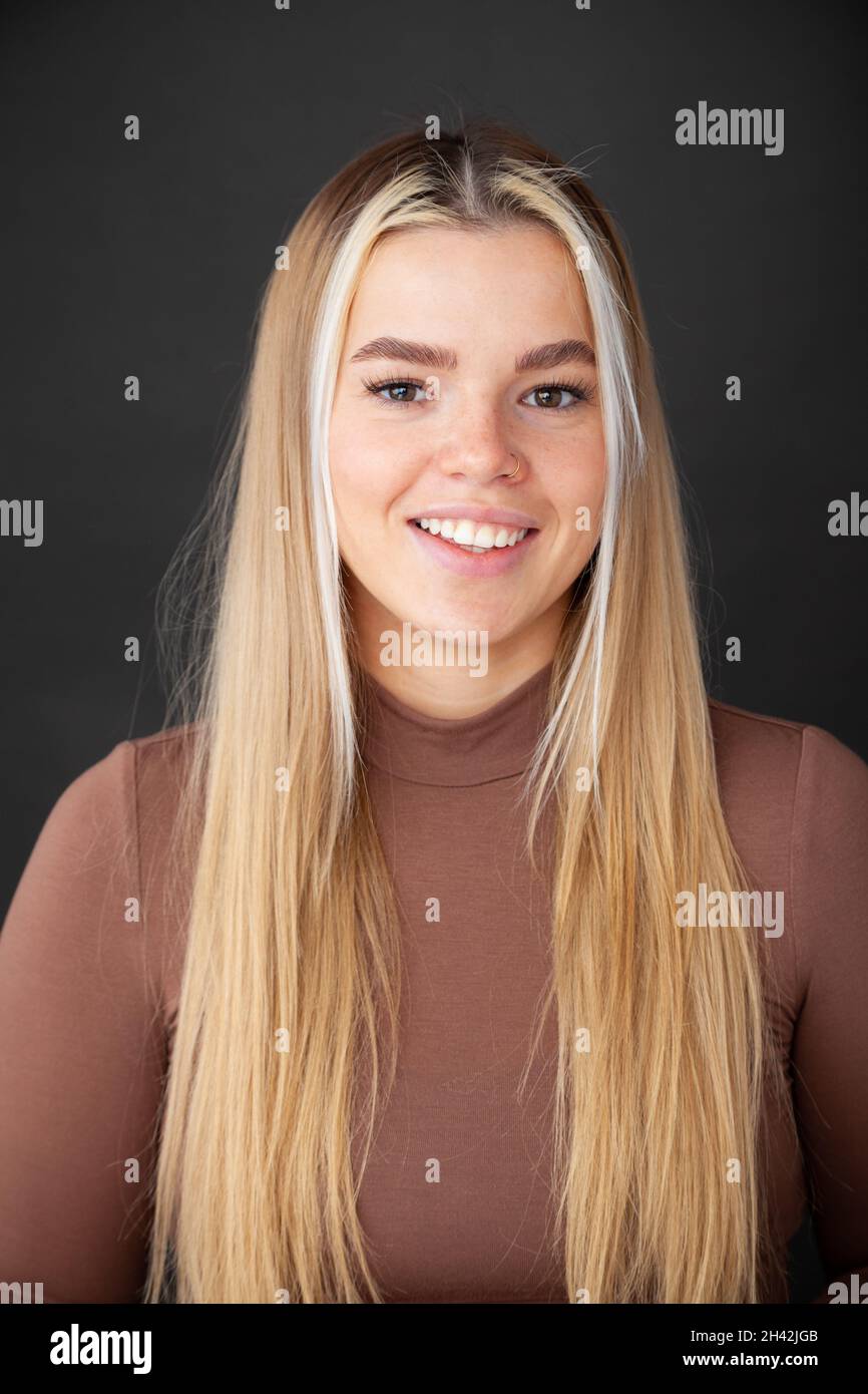 Una bella giovane donna con lunghi capelli biondi sorridenti verso la macchina fotografica Foto Stock