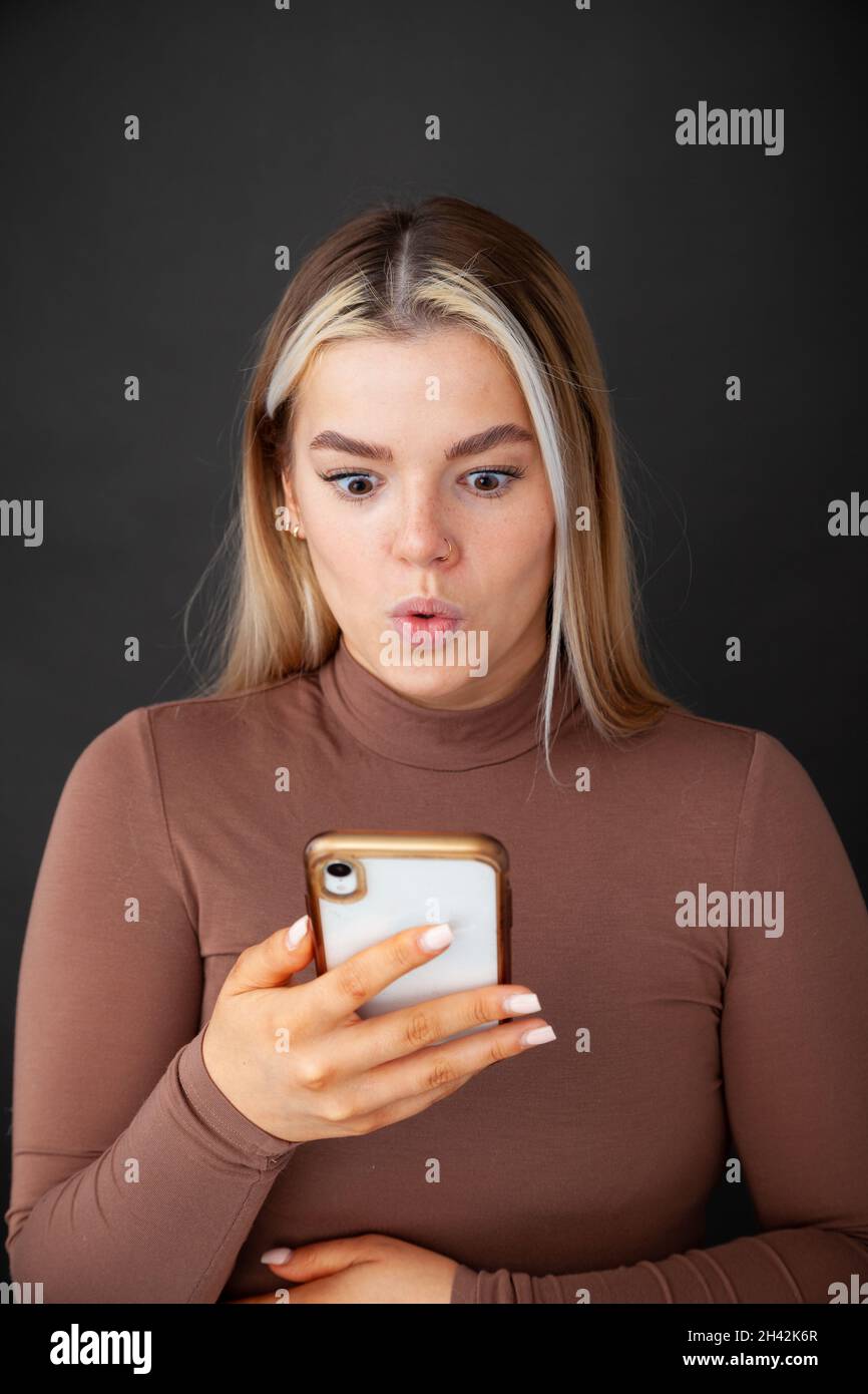Una bella donna di 20 anni che tiene in mano uno smartphone e guarda Foto Stock