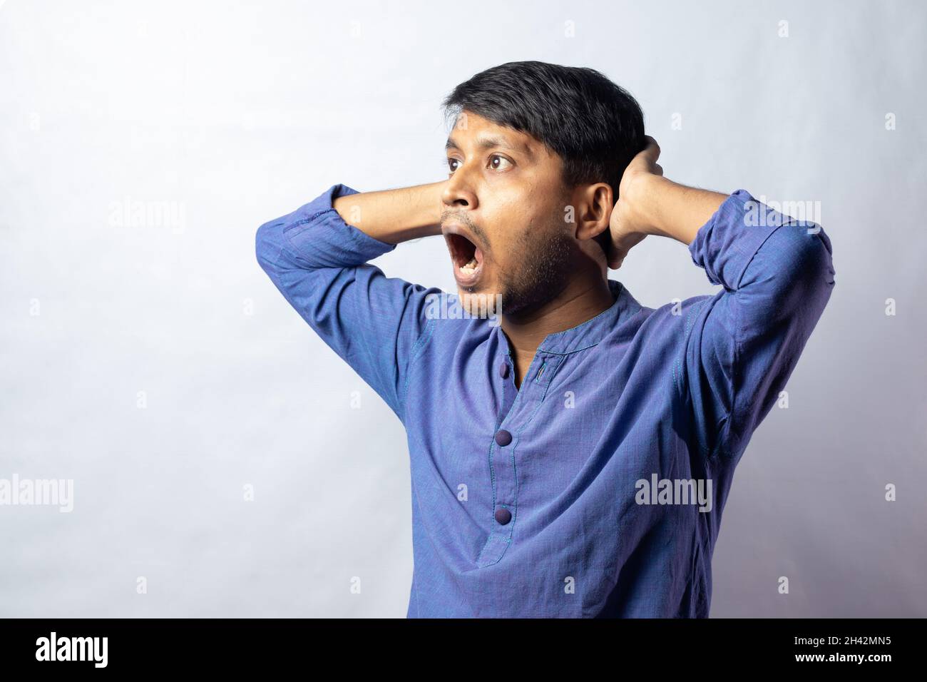 Un giovane maschio indiano in abito blu con aspetto sorpreso su sfondo bianco Foto Stock