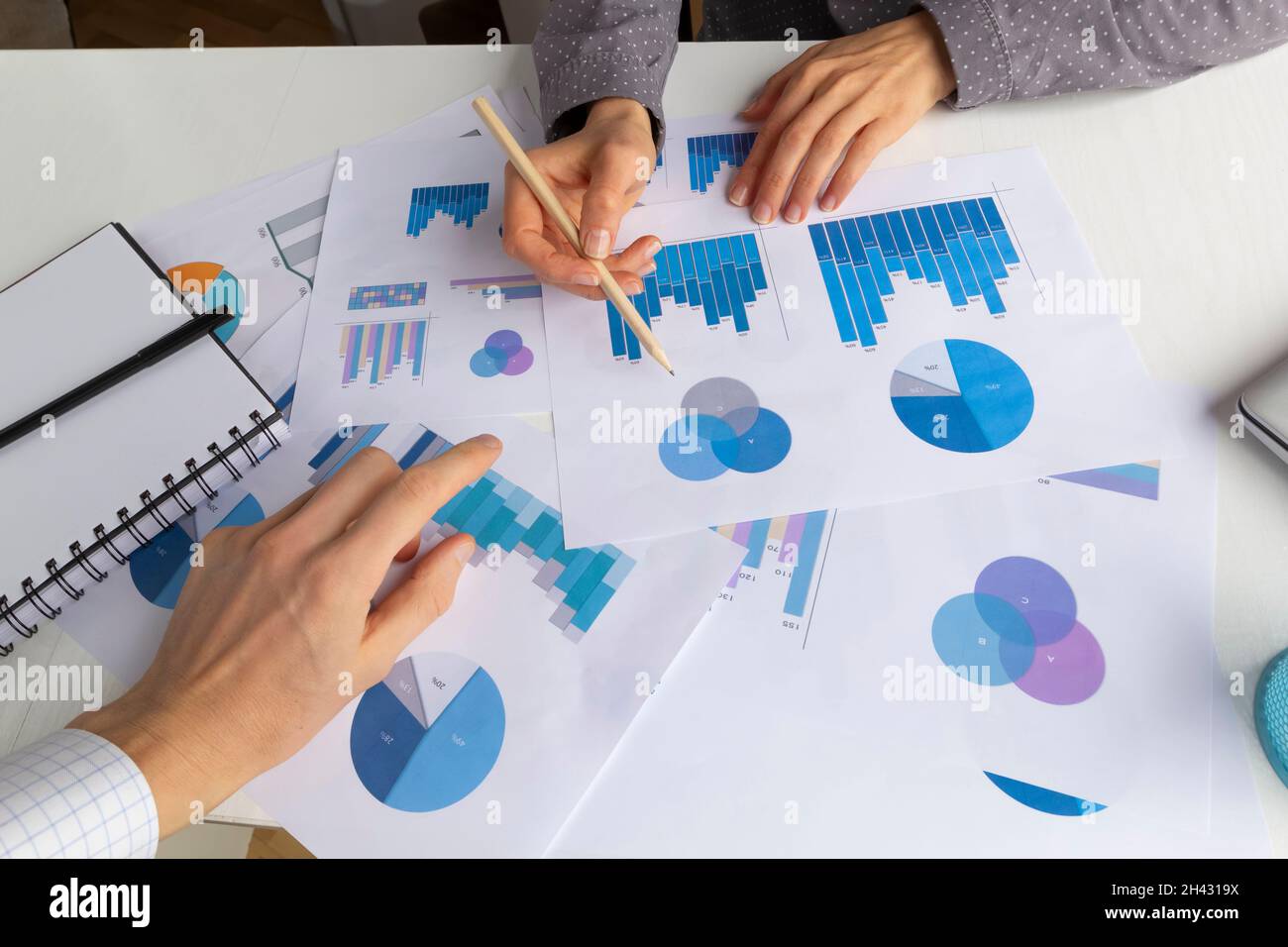 Un team di persone aziendali analizza report statistici e grafici di crescita sul desktop. Pianificazione dello sviluppo. Incontro, brainstorming. Foto Stock