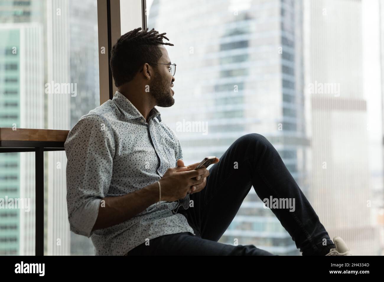 Sognante spensierato uomo da corsa misto utilizzando il cellulare. Foto Stock