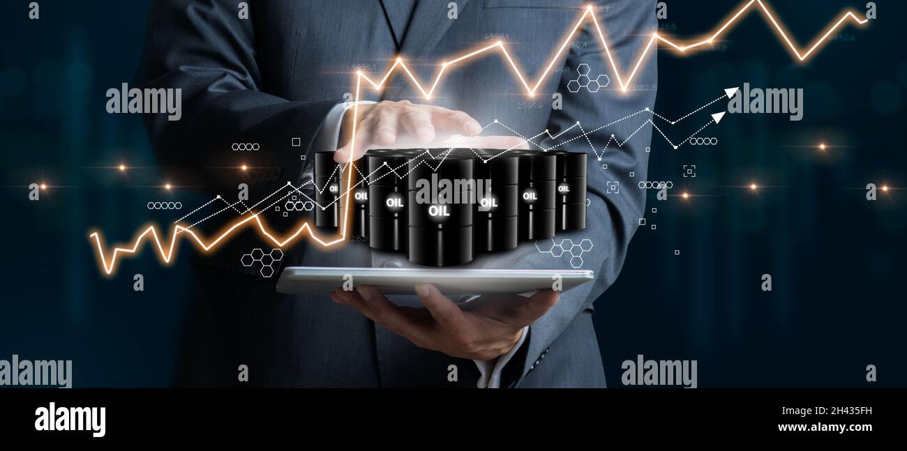 Imprenditore che detiene un gruppo di barili di petrolio con grafici del mercato azionario come concetto di materia prima. Concetto di crisi finanziaria mondiale. Giù di oi Foto Stock
