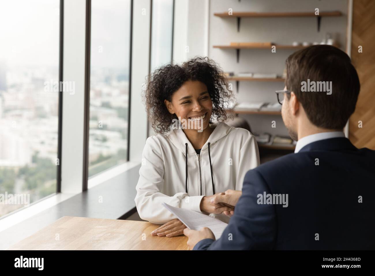 Felice candidato africano americano scuotendo le mani con il datore di lavoro maschile. Foto Stock