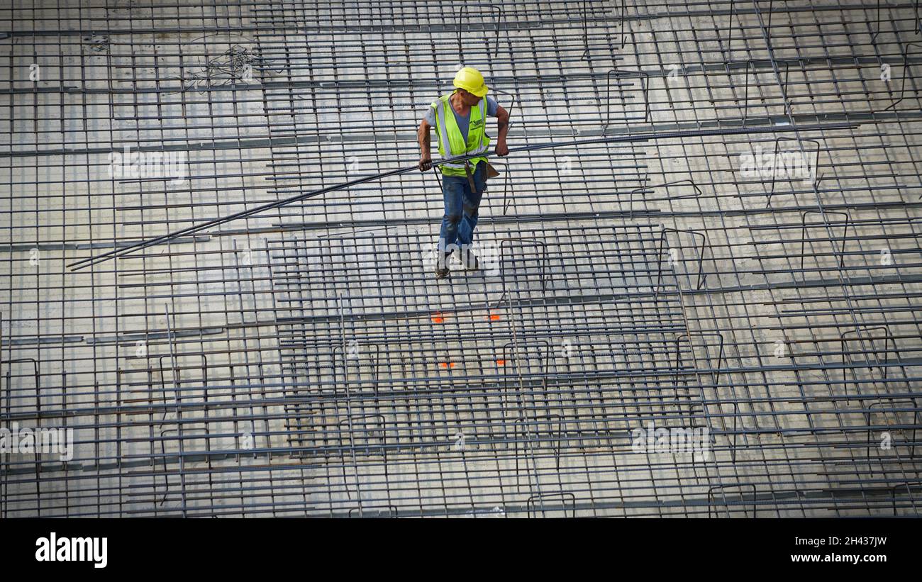 Operai edili che assemblano barre di rinforzo in acciaio sul sito di un nuovo edificio. Milano, Italia - Ottobre 2021 Foto Stock