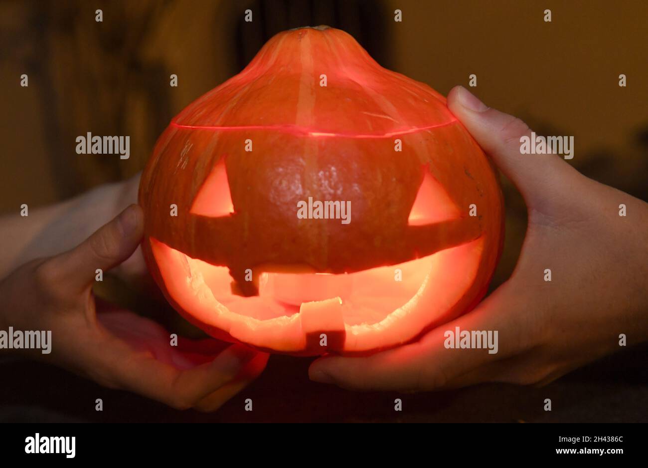 Monaco di Baviera, Germania. 31 ottobre 2021. Una zucca illuminata con una candela è posta su un pilastro del cancello giardino da residenti di una casa in serata ad Halloween. Halloween, una consuetudine la sera e la notte prima del giorno di tutti i Santi è diventata una data fissa per fantasmi, streghe e vampiri. Credit: Felix Hörhager/dpa/Alamy Live News Foto Stock