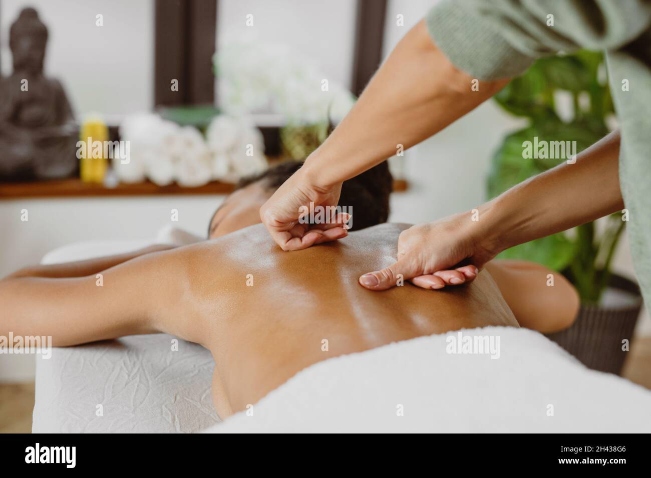 Donna afroamericana con massaggio alla schiena in un moderno salone termale. Foto Stock