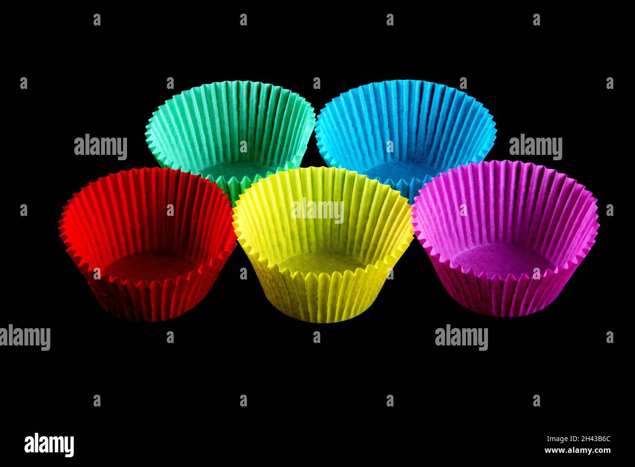 Piccoli contenitori di carta colorati per la cottura dei cupcake isolati su sfondo nero Foto Stock