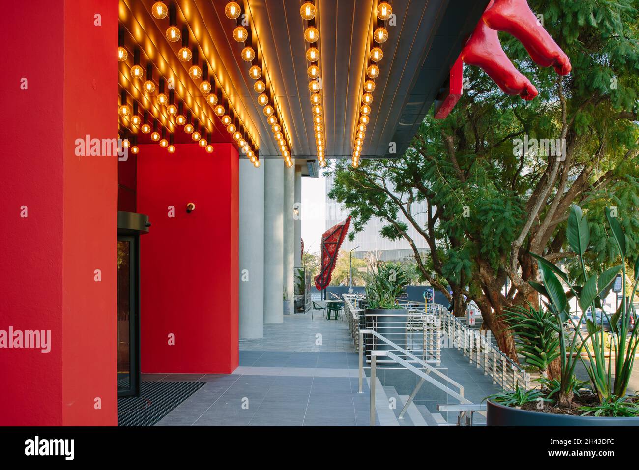 Avvicinamento ed entrata sotto la tettoia delle luci. Radisson RED Rosebank, Johannesburg, Sudafrica. Architetto: dhk Architects, 2021. Foto Stock