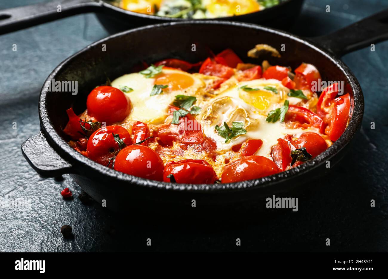 Padella con gustoso Shakshouka su sfondo nero Foto Stock