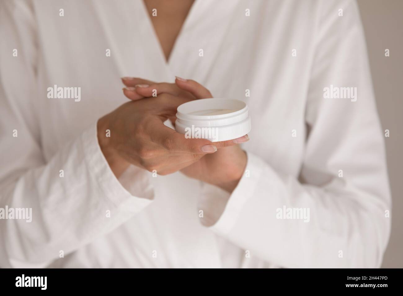 Giovane donna in accappatoio bianco applicazione crema mani, primo piano Foto Stock