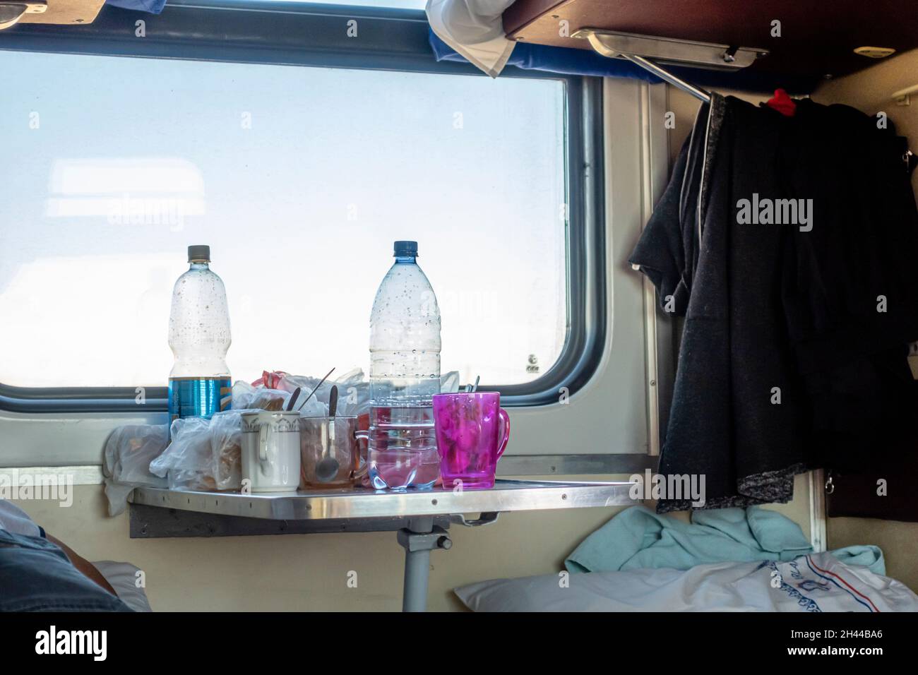 Bottiglie d'acqua di plastica, tazze e bicchieri su un tavolo in terza classe in auto condivisa, platzcart carrozza nel treno operato da Kazakhstan Temir Zholy Foto Stock