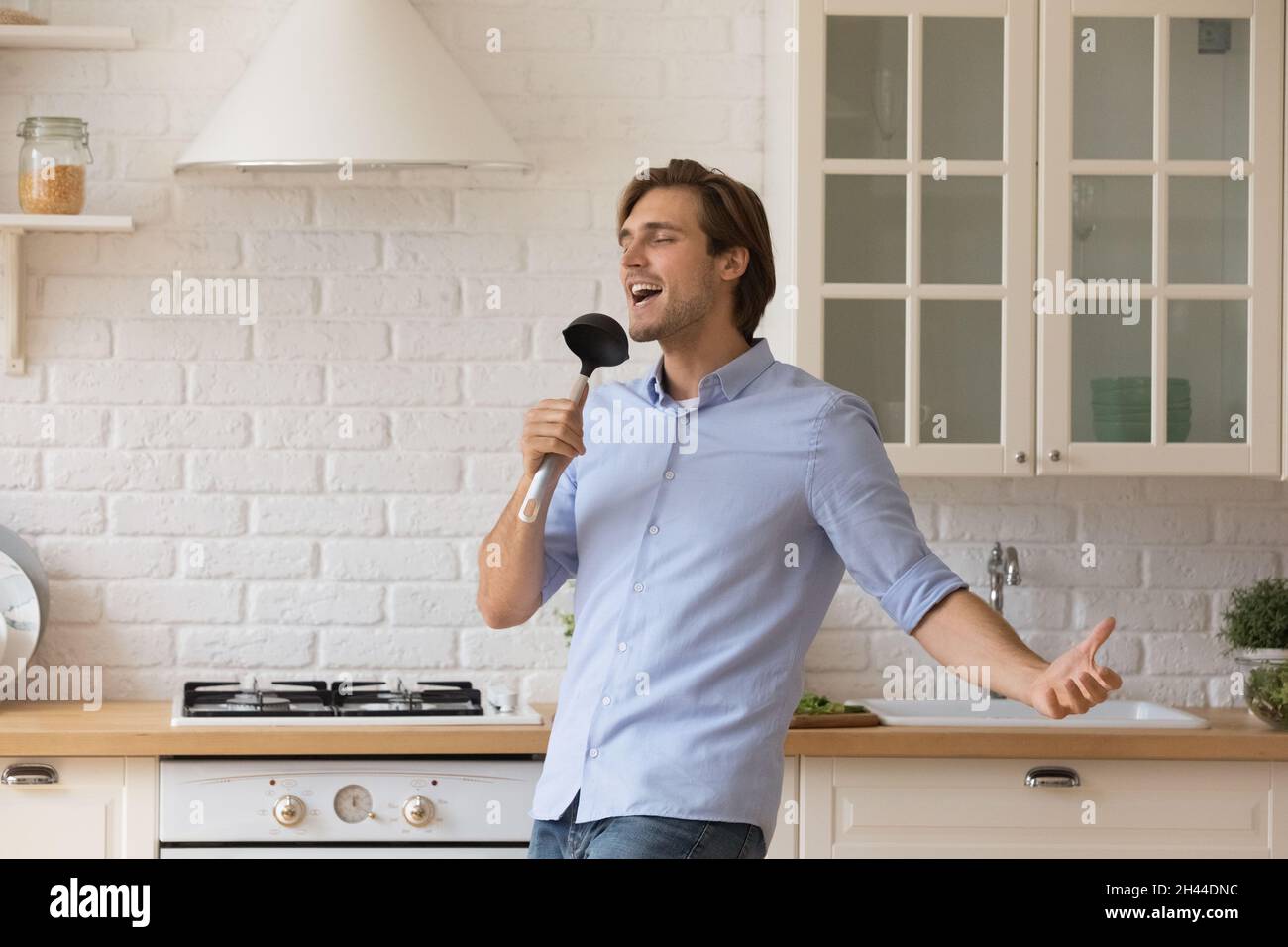 Uomo che canta la canzone preferita in una danza ladle in cucina Foto Stock
