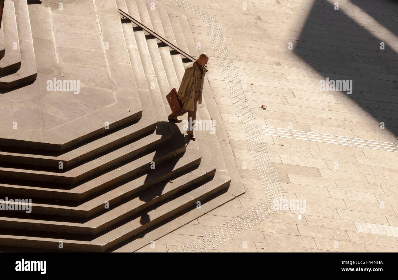 Belgrado, Serbia - 25 ottobre 2020: Un uomo calvo in tuta e cappotto che porta la valigetta a piedi da solo lungo le enormi scale pubbliche, alto angolo di vista in se Foto Stock