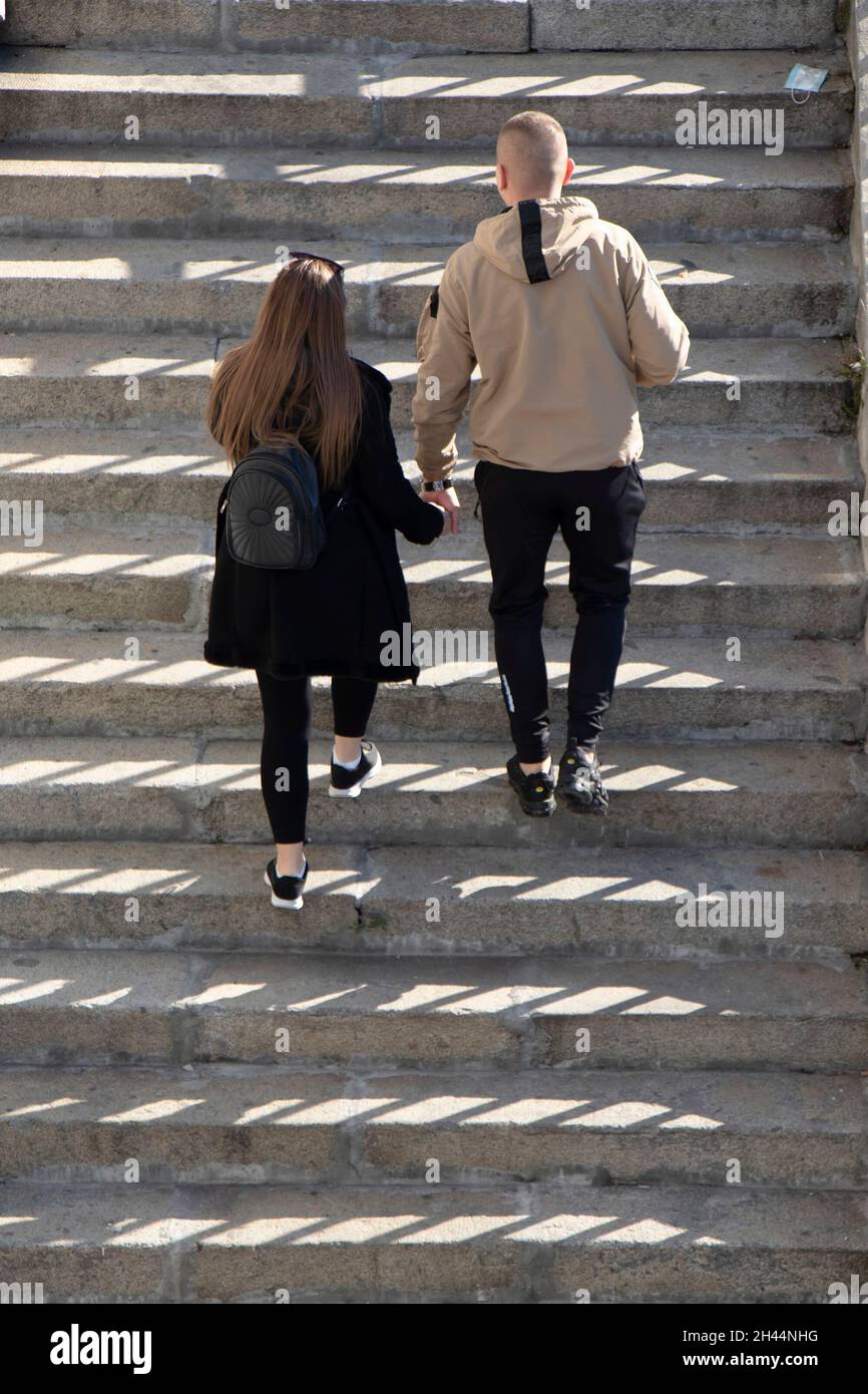 Belgrado, Serbia - 25 ottobre 2020: Giovane coppia che sale le scale pubbliche all'aperto, vista ad angolo alto da dietro Foto Stock