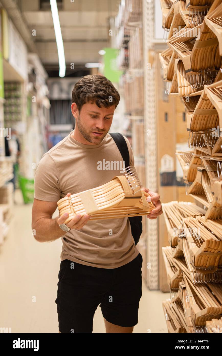 Casual tipo scelta imballato set di appendino di legno per i vestiti mentre shopping nel reparto dei beni domestici Foto Stock