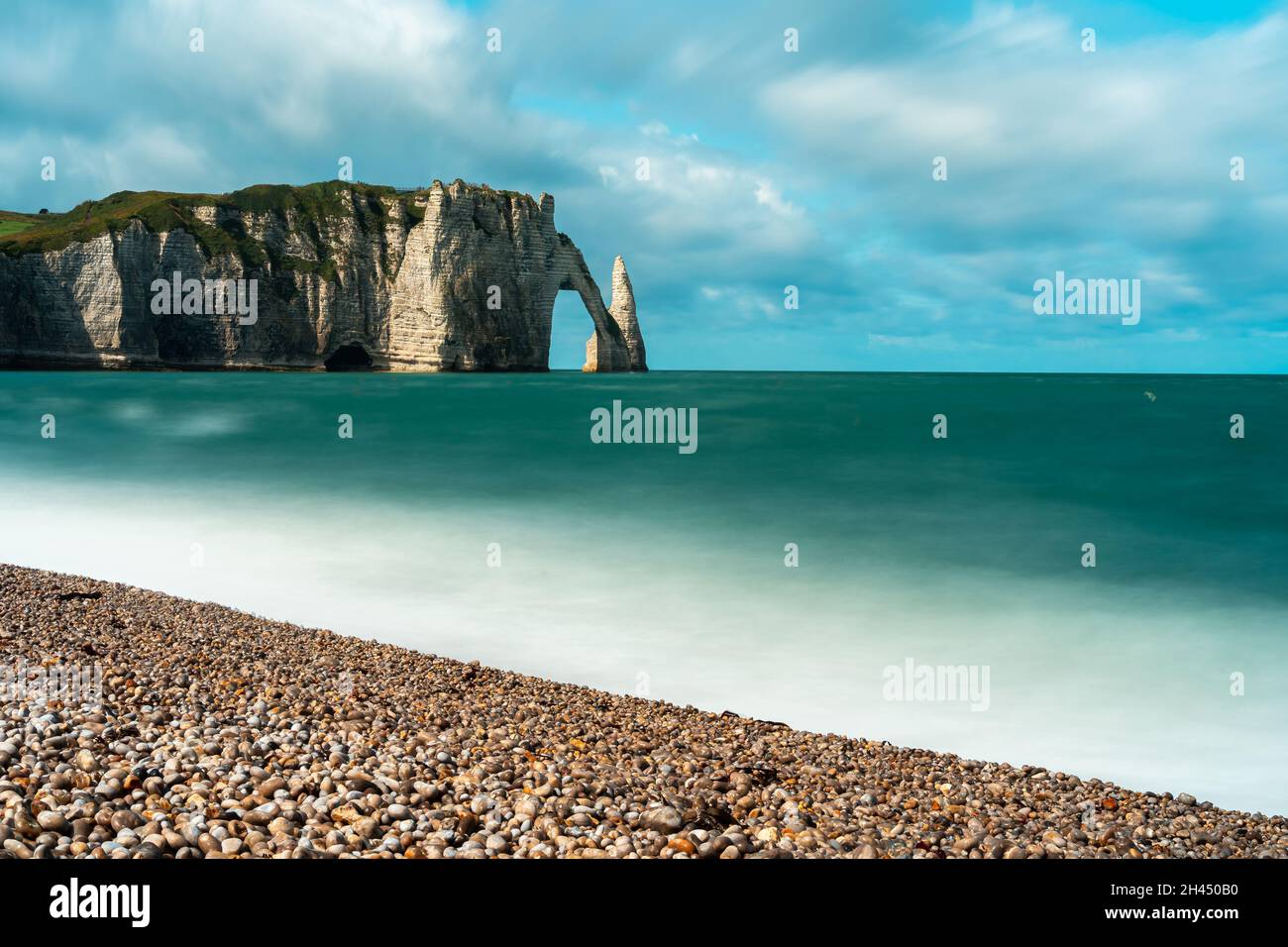 Etretat è meglio conosciuta per le sue scogliere di gesso, tra cui tre archi naturali e una formazione appuntita chiamata Aiguille o l'ago Foto Stock