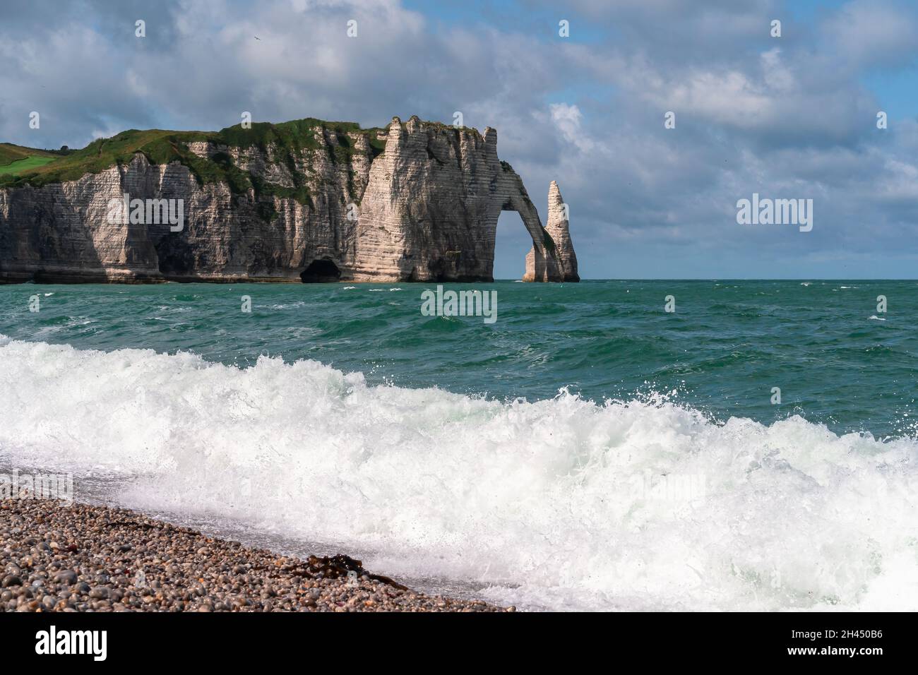 Etretat è meglio conosciuta per le sue scogliere di gesso, tra cui tre archi naturali e una formazione appuntita chiamata Aiguille o l'ago Foto Stock