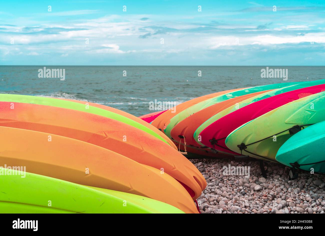 Kayak di diversi colori accatastati sulle rive dell'oceano Atlantico a Etretat, in Normandia Foto Stock