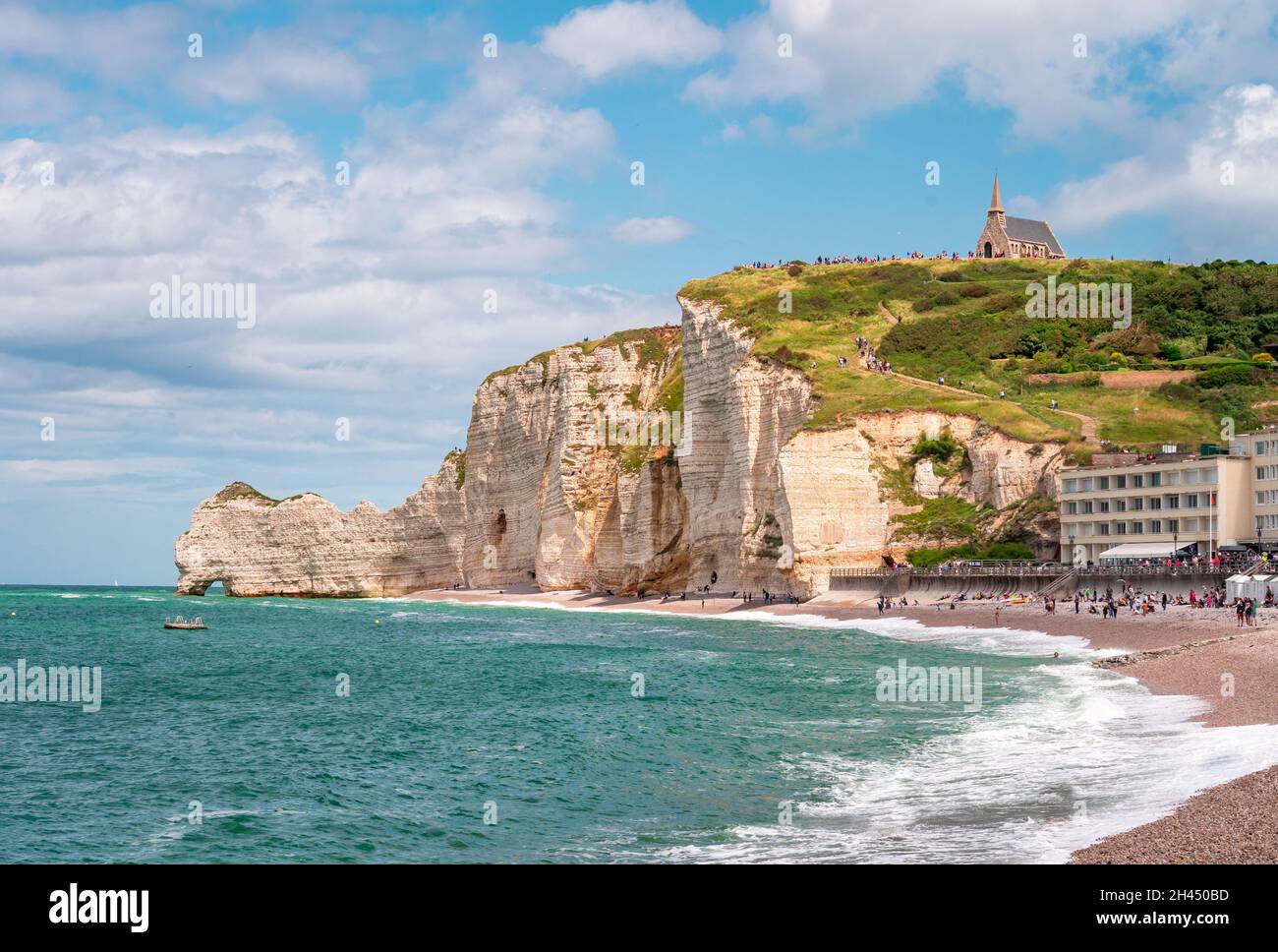 Etretat è meglio conosciuta per le sue scogliere di gesso, tra cui tre archi naturali e una formazione appuntita chiamata Aiguille o l'ago Foto Stock