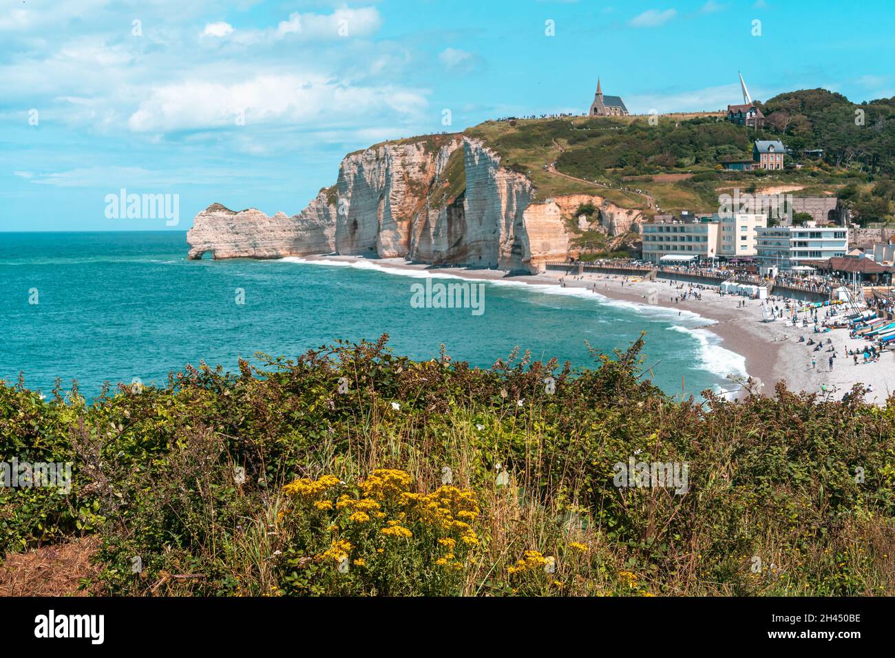Etretat è meglio conosciuta per le sue scogliere di gesso, tra cui tre archi naturali e una formazione appuntita chiamata Aiguille o l'ago Foto Stock