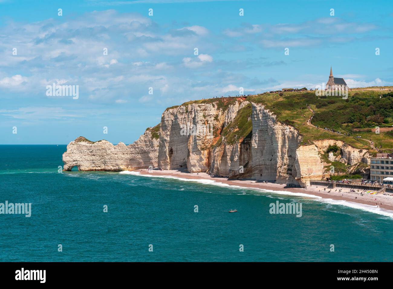 Etretat è meglio conosciuta per le sue scogliere di gesso, tra cui tre archi naturali e una formazione appuntita chiamata Aiguille o l'ago Foto Stock